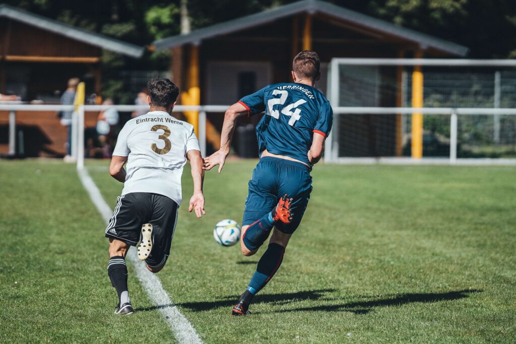サッカーボールを全力で追いかける二人の選手