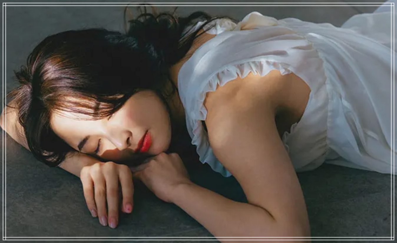 白いドレスを着て寝転がり目を閉じる西村美柚さん