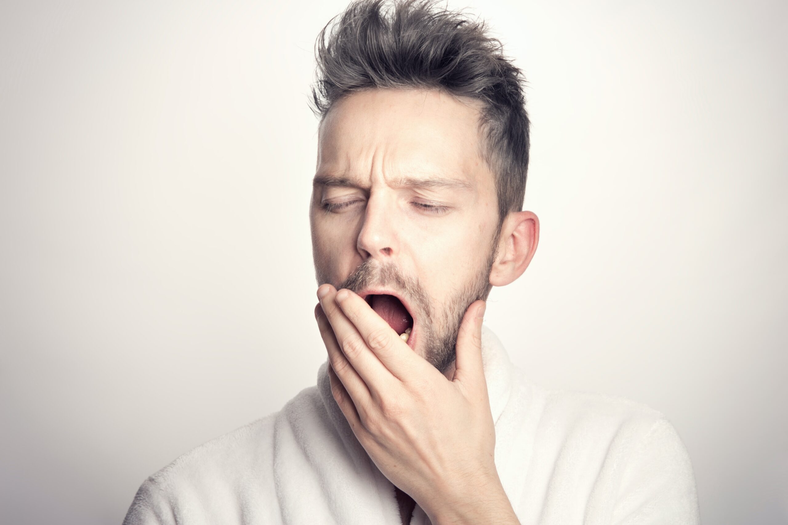左手で口を覆いながらあくびをする男性