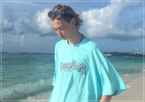 沖縄の海をバックに水色のTシャツを着た窪塚愛流