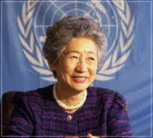 国連の旗の前で笑顔の緒方貞子さん